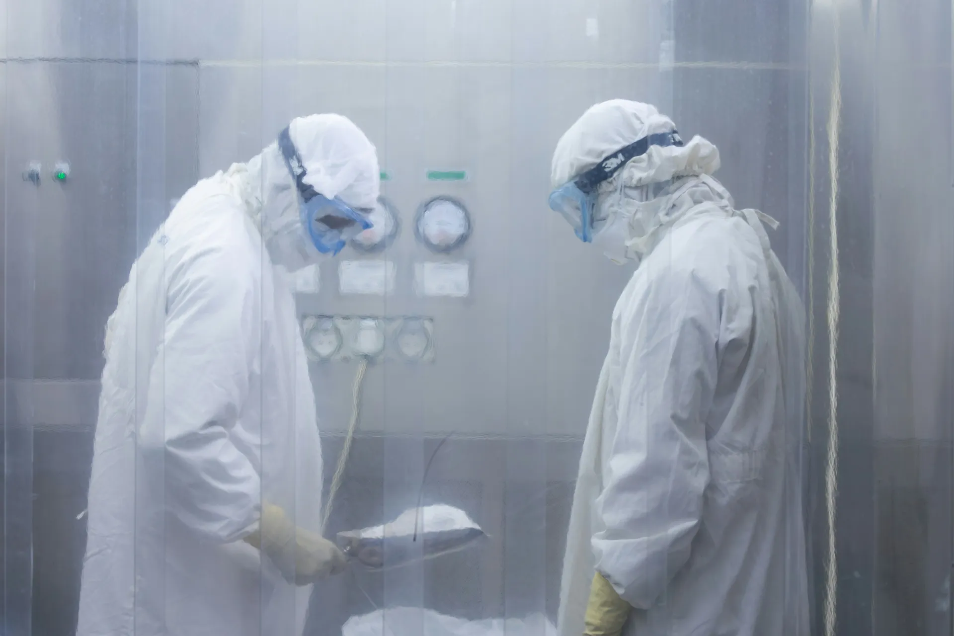 Technicians inspecting clean air device behind protective curtains